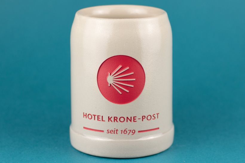 Steinkrug mit rot eingefärbter Gravur: Logo und Schriftzug „Hotel Krone-Post seit 1679“